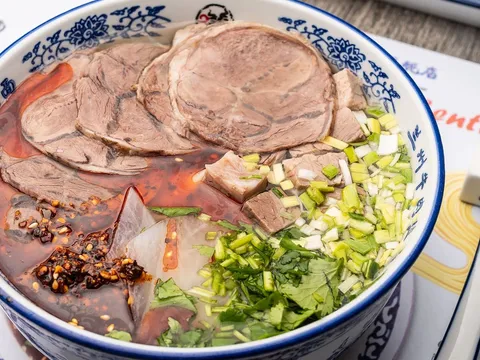 Bowl of Lanzhou hand-pulled beef noodle soup on a Lan Noodle placemat