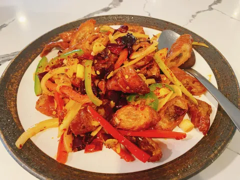 Sichuan-style wok-fried dish with dried chilies, sliced peppers and ginger on a plate at Cooking Girl