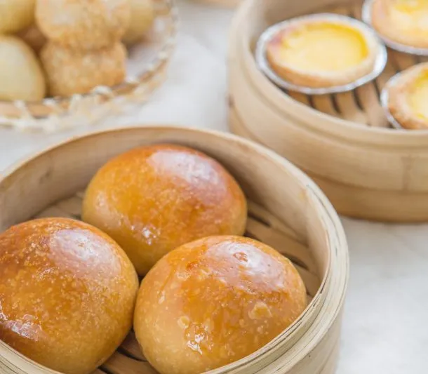 Baked BBQ pork buns in a bamboo steamer with egg tarts and sesame balls at All That 'N Dim Sum