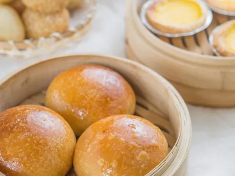 Baked BBQ pork buns in a bamboo steamer with egg tarts and sesame balls at All That 'N Dim Sum