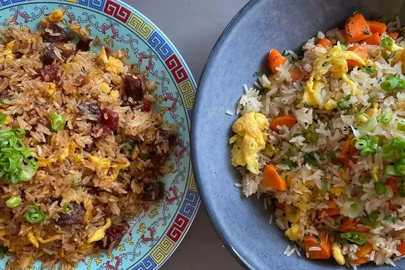 Two bowls of fried rice at Old Thousand in Austin — smoked-brisket fried rice on a patterned Chinese plate beside a bowl of egg-and-carrot fried rice topped with scallions
